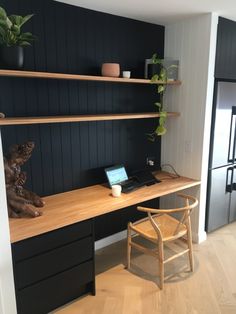 a desk with a laptop on top of it next to a wooden chair and shelves