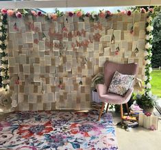 a chair sitting in front of a wall covered with paper and flowers on top of a rug