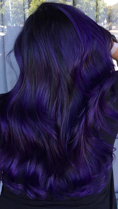 the back of a woman's head with dark purple hair and long wavy locks