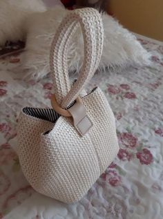 a white purse sitting on top of a bed