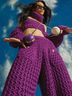 a woman in a purple knitted outfit holding a ball and chain around her waist