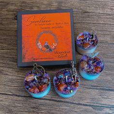 three small blue vases are sitting on a table next to an orange book and earrings