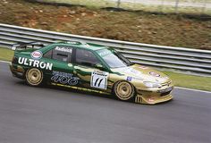 a green and gold car driving down a race track