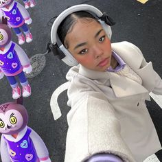 a woman taking a selfie with her headphones on and several stuffed animals in the background