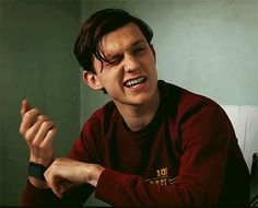 a young man in a red shirt holding his hand up