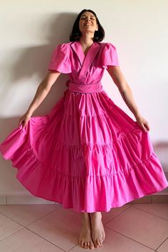 a woman in a pink dress standing against a wall