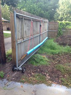 a wooden fence with a blue pipe attached to it and some grass in the yard