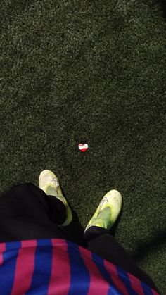 a person's feet in striped pants and sneakers on the grass near a red, white and blue frisbee