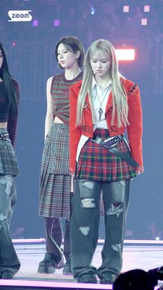 two girls in plaid outfits on stage with one girl wearing a red jacket and black pants