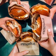 four people holding sandwiches in their hands with the words eggplant written on them