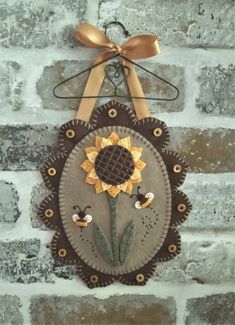 a sunflower hanging on the side of a brick wall with a ribbon around it