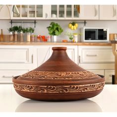 a brown vase sitting on top of a counter in a kitchen next to white cabinets