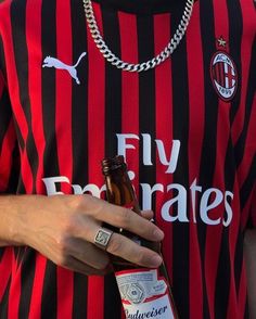 a man wearing a red and black striped shirt holding a beer in his left hand