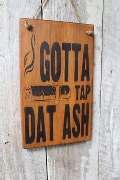 a wooden sign that says,'gota tap dat ash'hanging on a wall