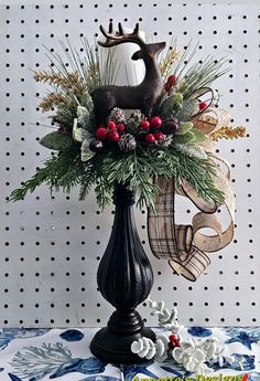 a black vase filled with greenery and antlers on top of a blue table cloth