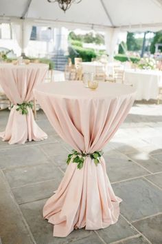 the tables are covered with pink cloths and green leaves on them for an elegant look