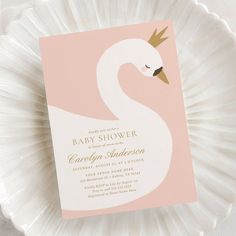 a pink and gold baby shower with a swan on it's head is sitting on a white plate