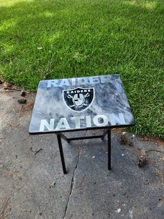 a black and white table sitting on top of a cement ground next to green grass