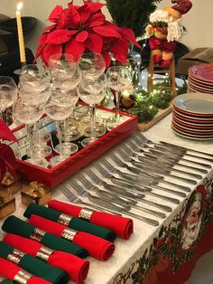 a table topped with lots of red and green napkins next to silverware on top of a wooden tray