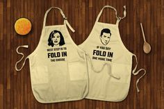 two aprons with the words, if you say fold in, and an orange next to them