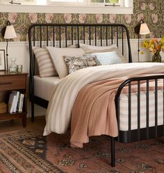 a bed sitting in a bedroom next to a dresser and lamp on top of a rug