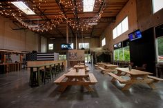 the inside of a building with several picnic tables and televisions hanging from the ceiling