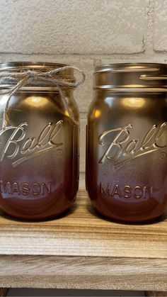 two mason jars sitting on top of a wooden shelf