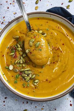 a bowl filled with carrot soup and topped with pumpkin seeds