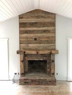 an empty room with a brick fireplace and wood paneling on the wall above it