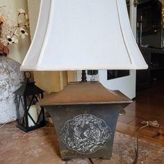 a lamp that is sitting on the floor in front of a wall with an ornate design