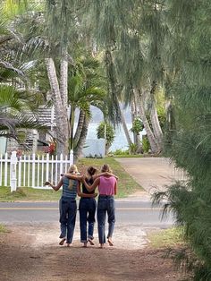 three women standing in the middle of a road with their arms wrapped around each other