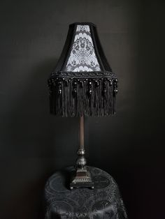 a lamp that is sitting on top of a stool with a black shade over it