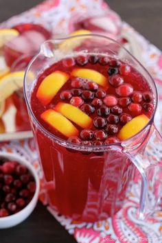 a pitcher filled with cranberry punch and sliced apples