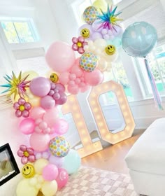 the balloon arch is decorated with smiley face balloons and embellishments for an 80th birthday celebration