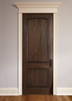 an empty room with a wooden door and hard wood flooring in front of it