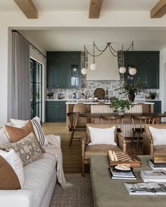 a living room filled with furniture next to a kitchen and dining room table covered in pillows