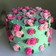 a blue cake with pink and green frosting roses on it's side, sitting on a white plate