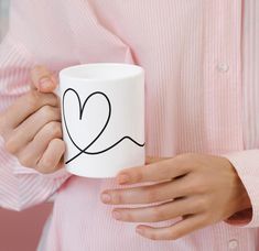 a person holding a coffee mug with a heart drawn on it's side and hands