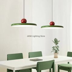 a white table with green chairs and two red apples hanging from it's lights