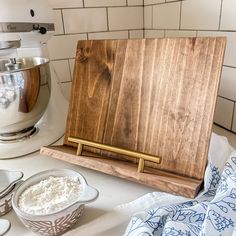 a wooden cutting board sitting on top of a counter next to bowls and spoons