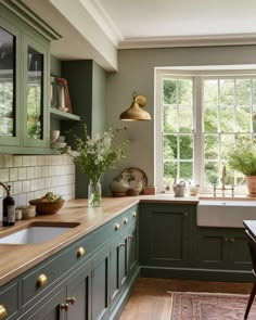 a kitchen filled with lots of green cabinets and counter top space next to a window