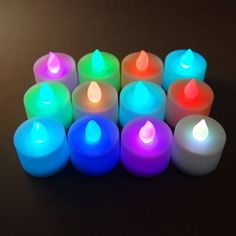 many lit candles are arranged in a row on a black surface with one candle glowing brightly