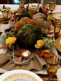 the table is set with pumpkins, flowers and other autumn decorations for thanksgiving dinner