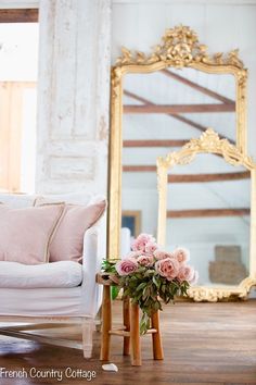 a white couch sitting in front of a mirror on top of a wooden floor