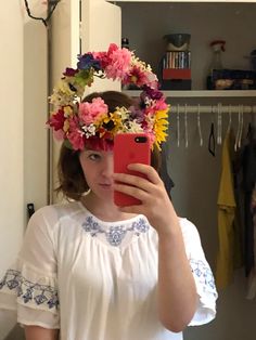 a woman taking a selfie with flowers in her hair while wearing a flower crown