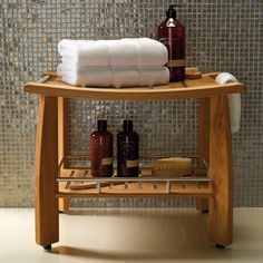 a wooden stand with towels and soaps on it in front of a tiled wall