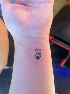 a small wrist tattoo with an angel and paw prints on the left side of the wrist