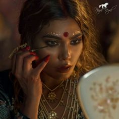 a woman with makeup on her face holding a mirror