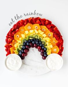 a rainbow made out of fruit and yogurt sits on a plate with the words eat the rainbow written above it