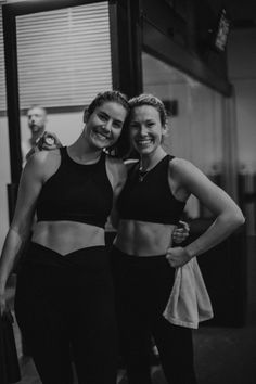 two women standing next to each other in front of a mirror wearing sports bras